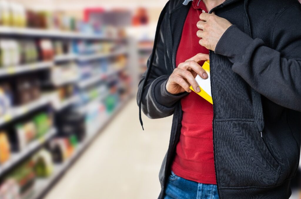 Ladendiebstahl im Einzelhandel. Mann stiehlt im Supermarkt
